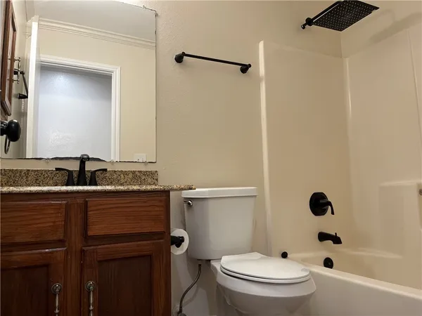 a bathroom with a granite countertop bathtub shower sink vanity and toilet