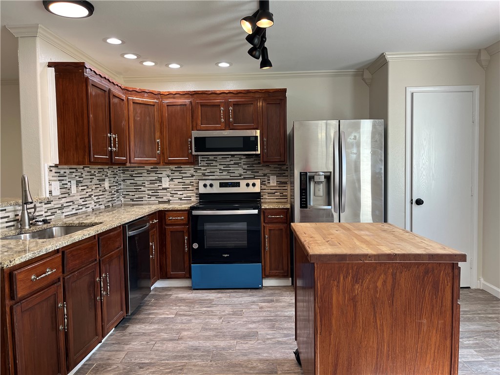 1219 Sacramento Street Portland, TX 78374 - Photo 5 of 40 a kitchen with stainless steel appliances kitchen island granite countertop a refrigerator stove and sink