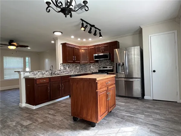 a large kitchen with stainless steel appliances kitchen island granite countertop a refrigerator a stove a sink and a microwave