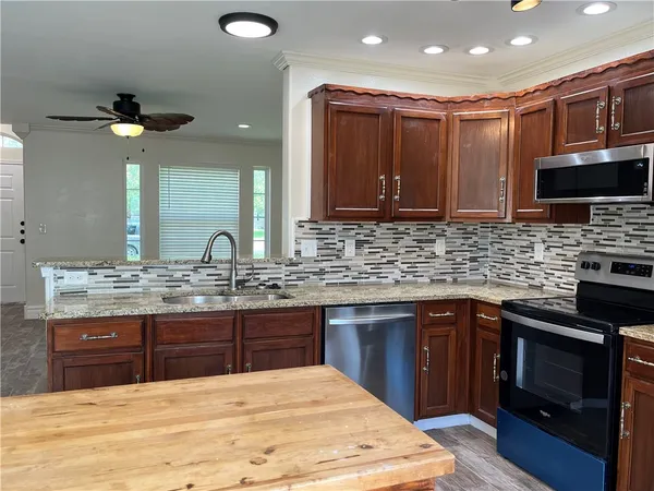 a kitchen with kitchen island granite countertop a sink cabinets and stainless steel appliances
