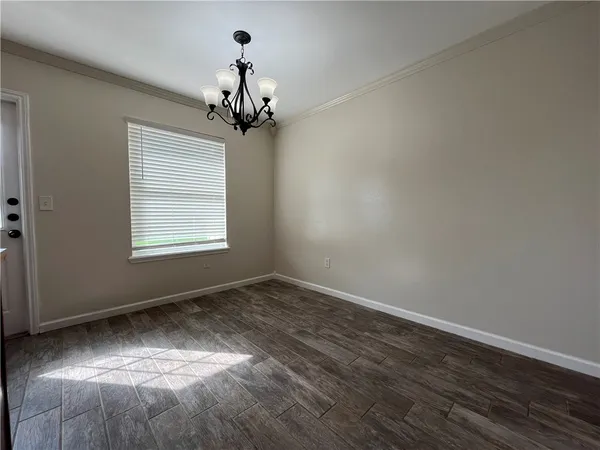 an empty room with wooden floor chandelier and windows