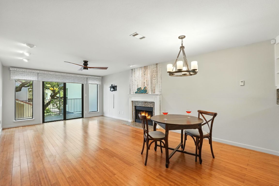 2918 Ranch Road 620 North, Unit C115 Austin, TX 78734 - Photo 12 of 39 Dining room with a fireplace, light wood-type flooring, ceiling fan, a chandelier, and a wall of windows