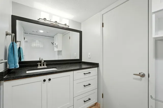 a bathroom with a granite countertop sink and a mirror