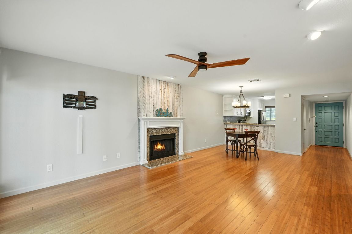 2918 Ranch Road 620 North, Unit C115 Austin, TX 78734 - Photo 4 of 39 Living area with a ceiling fan, light wood finished floors, a lit fireplace, a chandelier, and recessed lighting