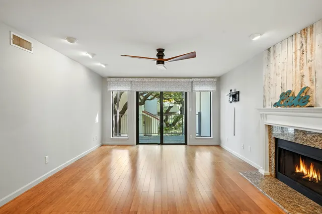 a view of a livingroom with wooden floor a fireplace and windows