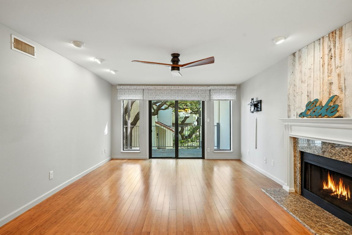2918 Ranch Road 620 North, Unit C115 Austin, TX 78734 - Photo 5 of 39 Unfurnished living room featuring a ceiling fan, wood finished floors, and a fireplace