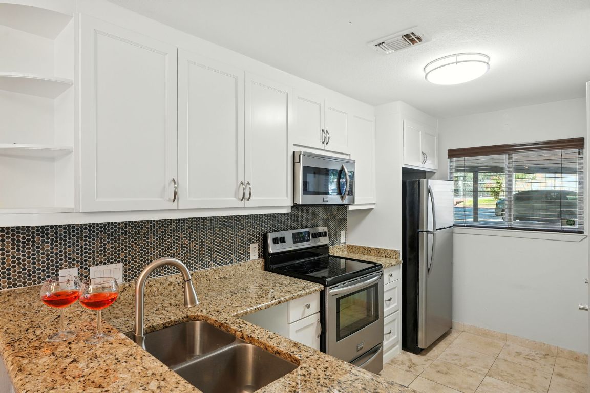 2918 Ranch Road 620 North, Unit C115 Austin, TX 78734 - Photo 9 of 39 Kitchen featuring stainless steel appliances, open shelves, tasteful backsplash, white cabinets, and light stone countertops