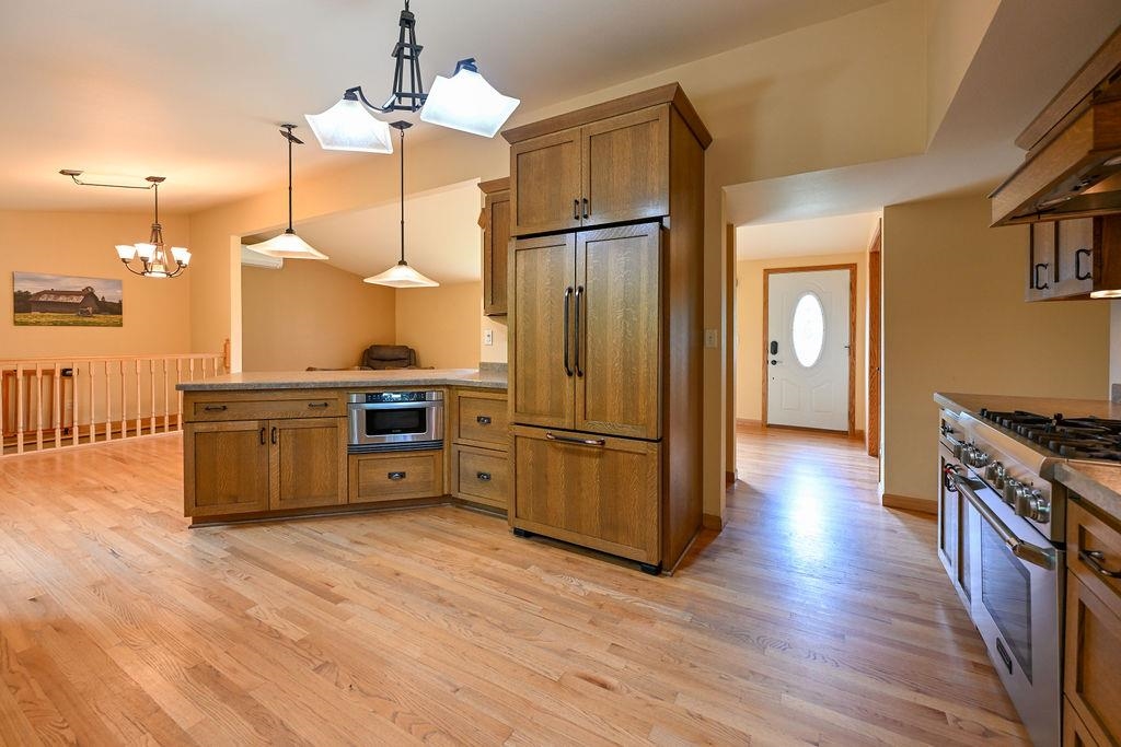 3705 County Rd D Poplar, WI 54864 - Photo 8 of 20 Kitchen featuring brown cabinets, high end appliances, a peninsula, light wood-style flooring, and pendant lighting
