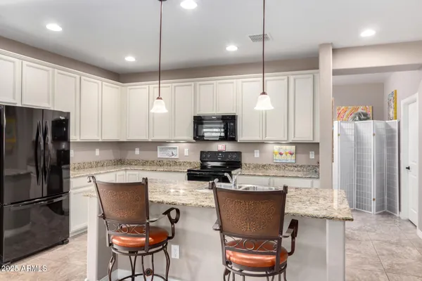a kitchen with stainless steel appliances granite countertop a refrigerator a stove a sink a dining table and chairs