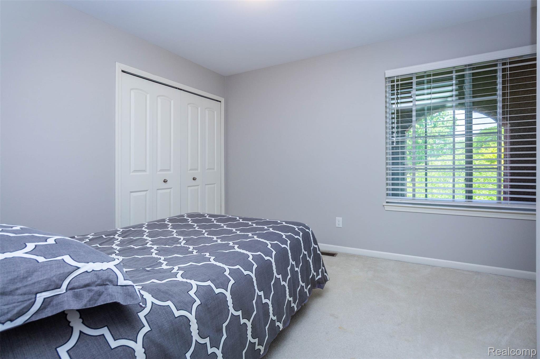 36039 Curtis Road Livonia, MI 48152 - Photo 29 of 61 Bedroom featuring neutral wall paint, light-toned carpet flooring, white bi-fold closet doors, and a window with horizontal blinds