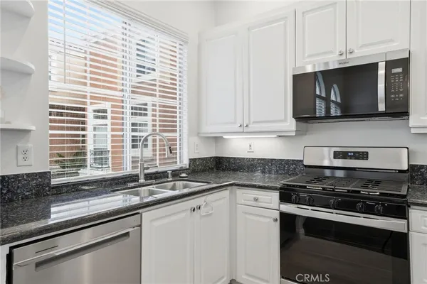 a kitchen with stainless steel appliances granite countertop white cabinets and a stove a oven