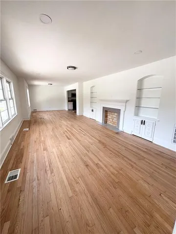 a view of empty room with wooden floor and windows