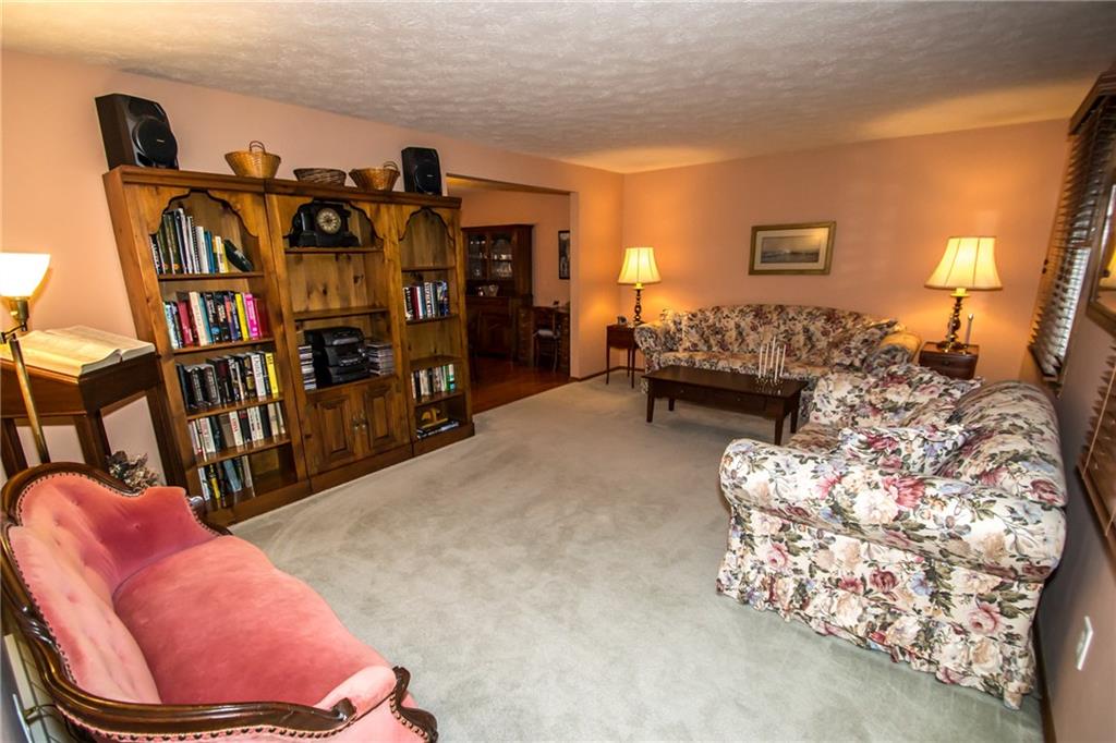 A spacious living room with neutral wall to wall carpeting.