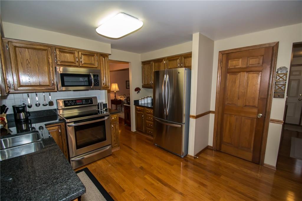 An updated kitchen with stainless steel appliances, hardwood flooring, granite counter tops, and a large breakfast area.