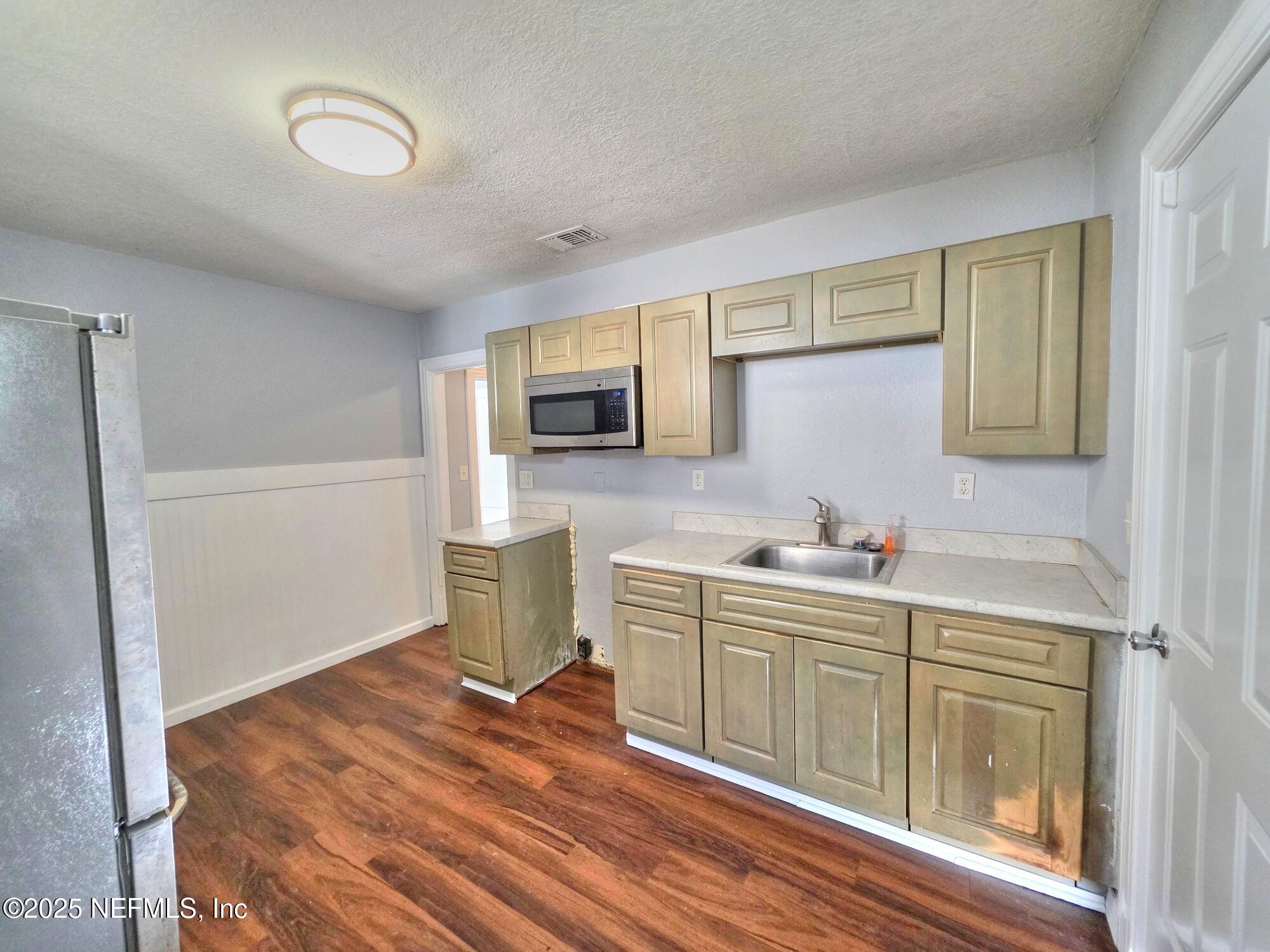 616 Woodbine Street Jacksonville, FL 32206 - Photo 11 of 25 a kitchen with stainless steel appliances a stove top oven a sink a refrigerator white cabinets and wooden floor
