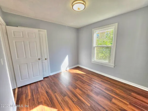 a view of empty room with wooden floor and fan
