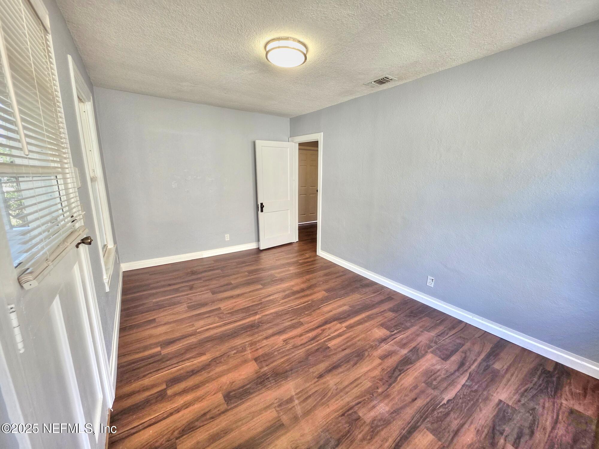 616 Woodbine Street Jacksonville, FL 32206 - Photo 7 of 25 a view of an empty room with wooden floor and a window