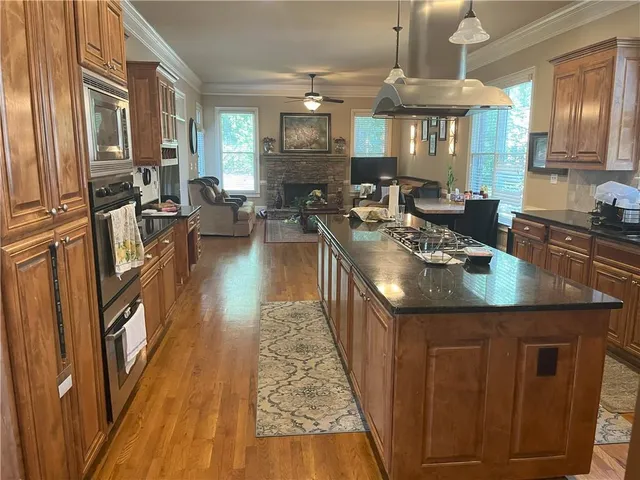 a kitchen with counter top space appliances wooden floor and windows