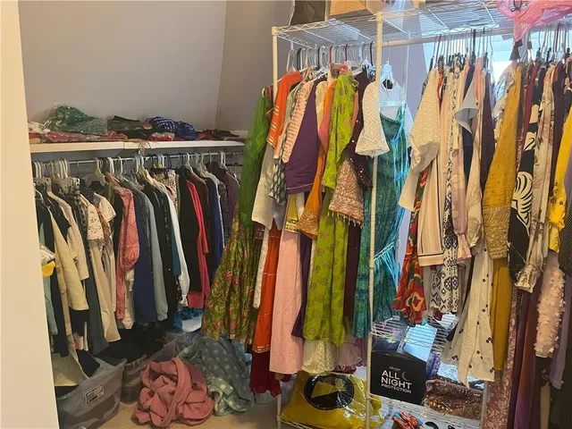 a view of walk in closet with clothes and shoes