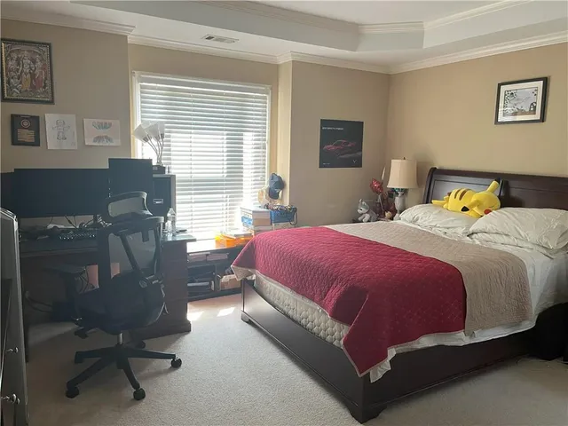 a spacious bedroom with a bed a desk chair and a window