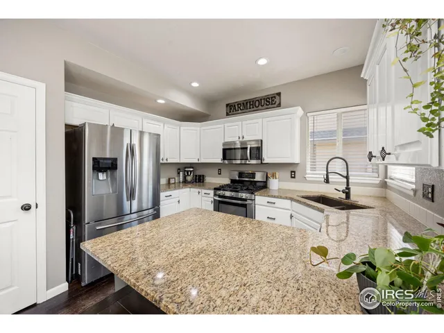 a kitchen with stainless steel appliances kitchen island granite countertop a refrigerator and a sink