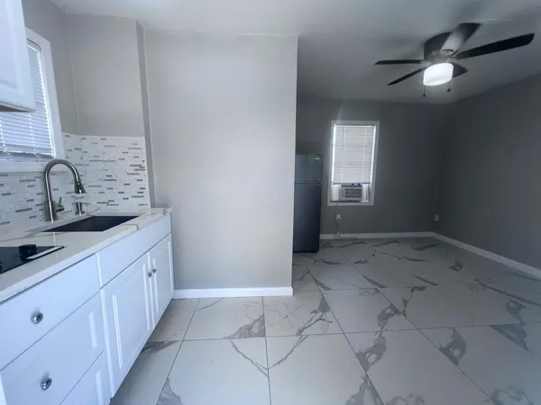 an empty room with chandelier fan and windows