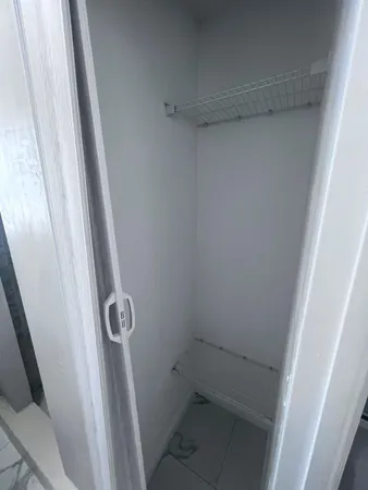 a view of a refrigerator in kitchen and an empty room