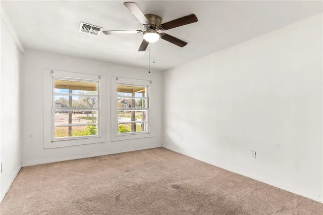 a view of a big room with windows and chandelier fan