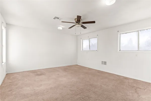 an empty room with windows and fan