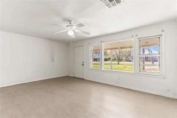 an empty room with a window and a fan