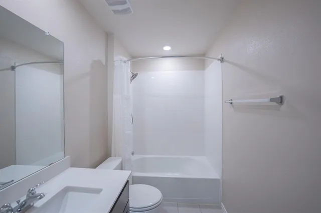 a bathroom with a granite countertop bathtub shower sink vanity and toilet