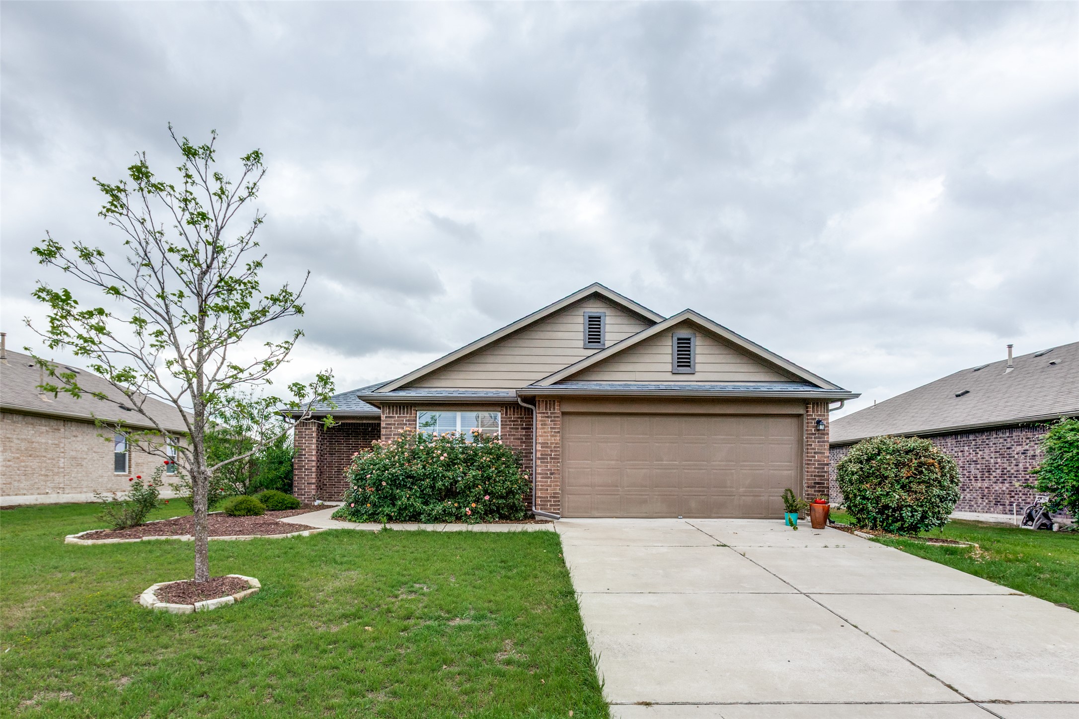 2909 Centrum Drive Austin, TX 78754 - Photo 2 of 30 The property features a brick exterior with tan siding, an attached garage, and a concrete driveway