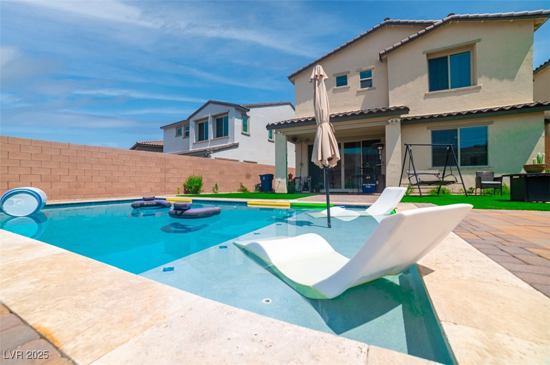 View of swimming pool with a patio and a fenced backyard