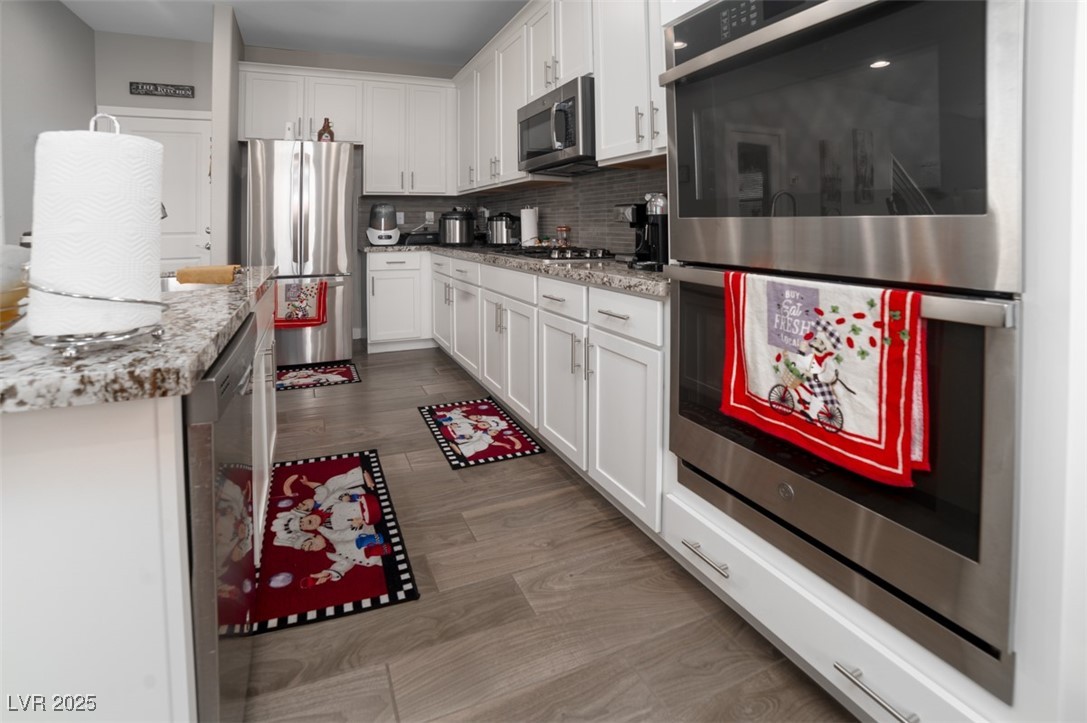 111 Verde Rosa Drive Henderson, NV 89011 - Photo 16 of 51 Kitchen featuring stainless steel appliances, white cabinetry, backsplash, and dark wood-style floors