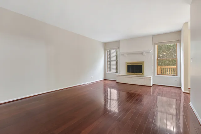 a view of empty room with wooden floor and fireplace