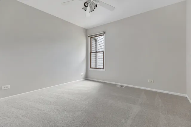 an empty room with a window and a ceiling fan