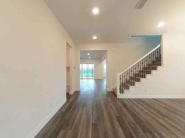 a view of a hallway with wooden floor and a potted plant