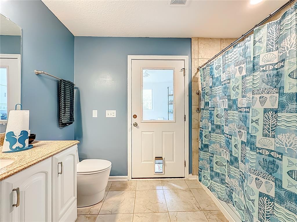 6380 Bahaia Road Fleming Island, FL 32003 - Photo 56 of 77 a bathroom with a granite countertop sink a toilet a mirror and shower