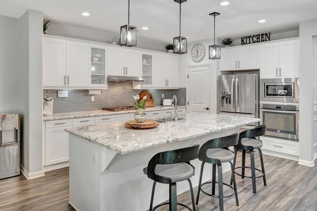21408 Trail Ridge Drive Escondido, CA 92029 - Photo 9 of 50 a kitchen with stainless steel appliances granite countertop a kitchen island a stove a refrigerator a sink a dining table and chairs with wooden floor