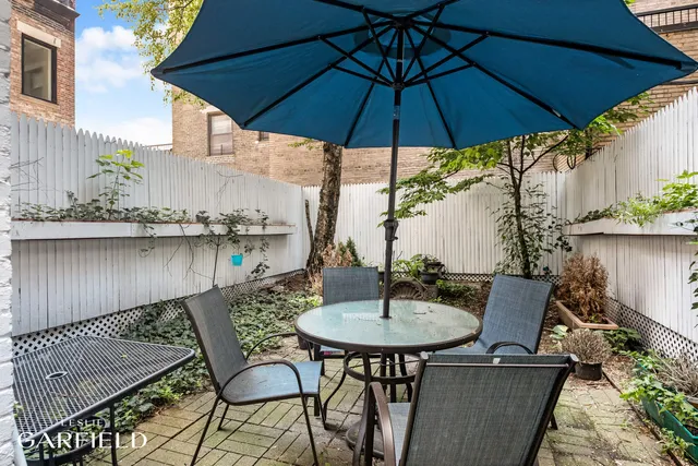 a patio with a table and chairs under an umbrella