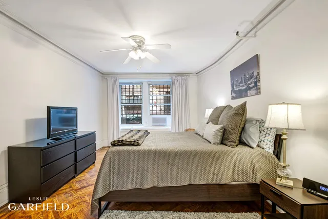 a bedroom with a bed and a flat tv screen on a dresser