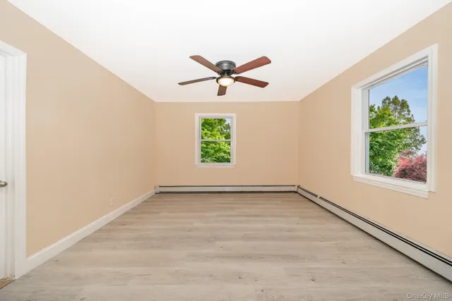 an empty room with windows and fan