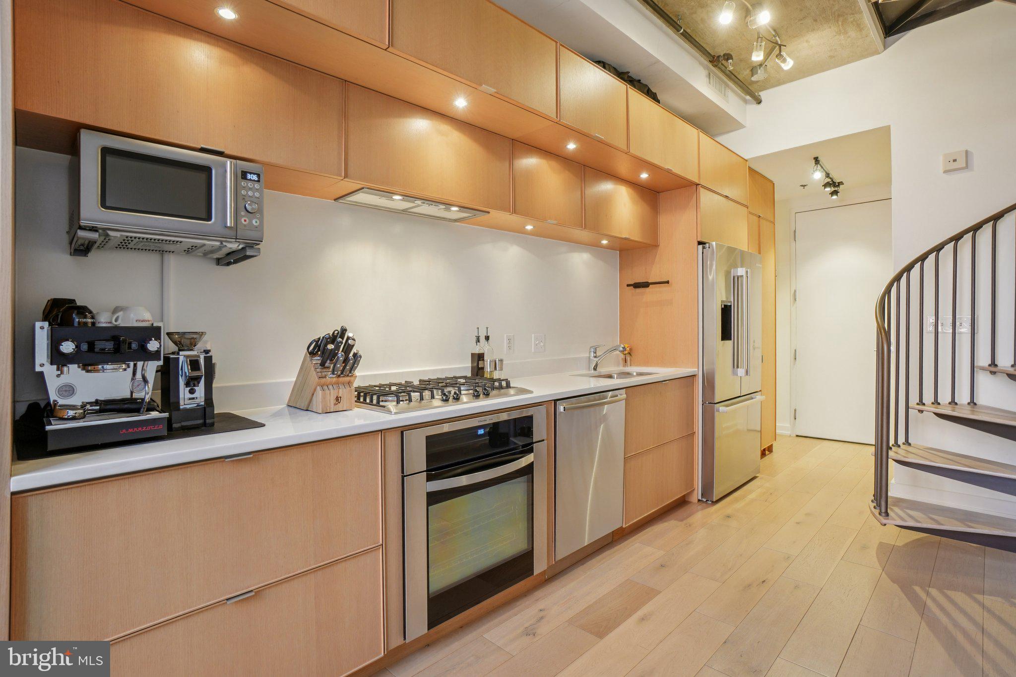 1515 15th Street Northwest, Unit 206 Washington, DC 20005 - Photo 6 of 32 a kitchen with stainless steel appliances granite countertop a sink a stove top oven and wooden floor