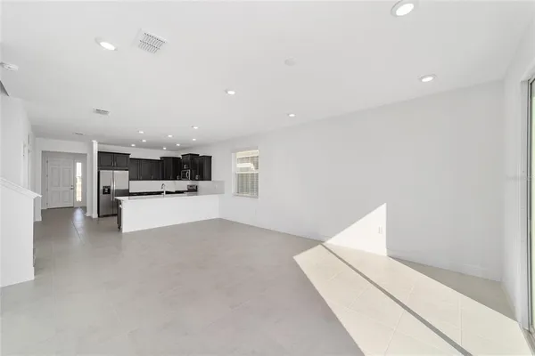 a view of kitchen with refrigerator and white cabinets