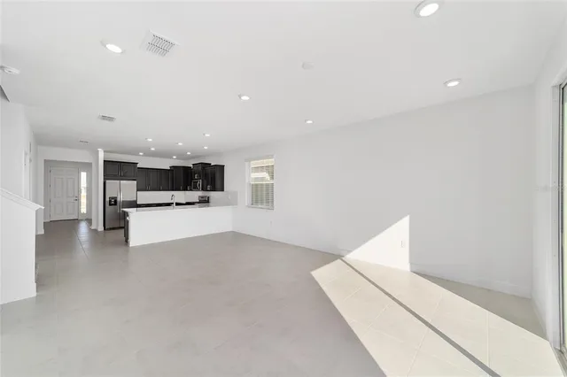 a view of kitchen with refrigerator and white cabinets