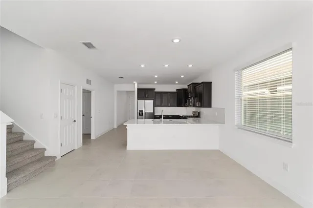a view of kitchen with stainless steel appliances kitchen island sink refrigerator and window