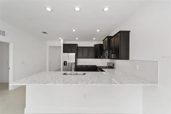 a kitchen with stainless steel appliances granite countertop a sink and a refrigerator