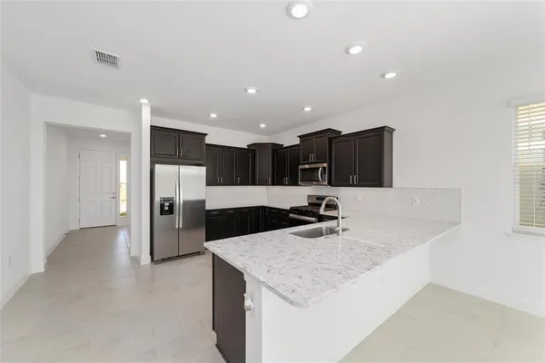 a kitchen with stainless steel appliances granite countertop a sink and a refrigerator