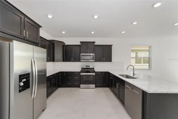 a kitchen with stainless steel appliances granite countertop a refrigerator a sink a stove a microwave and island