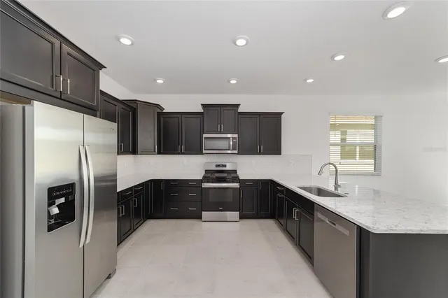 a kitchen with stainless steel appliances granite countertop a refrigerator a sink a stove a microwave and island